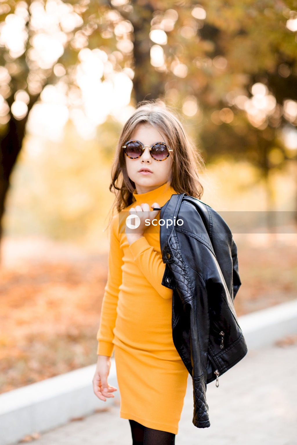 Woman in yellow long sleeve shirt and black scarf wearing black sunglasses