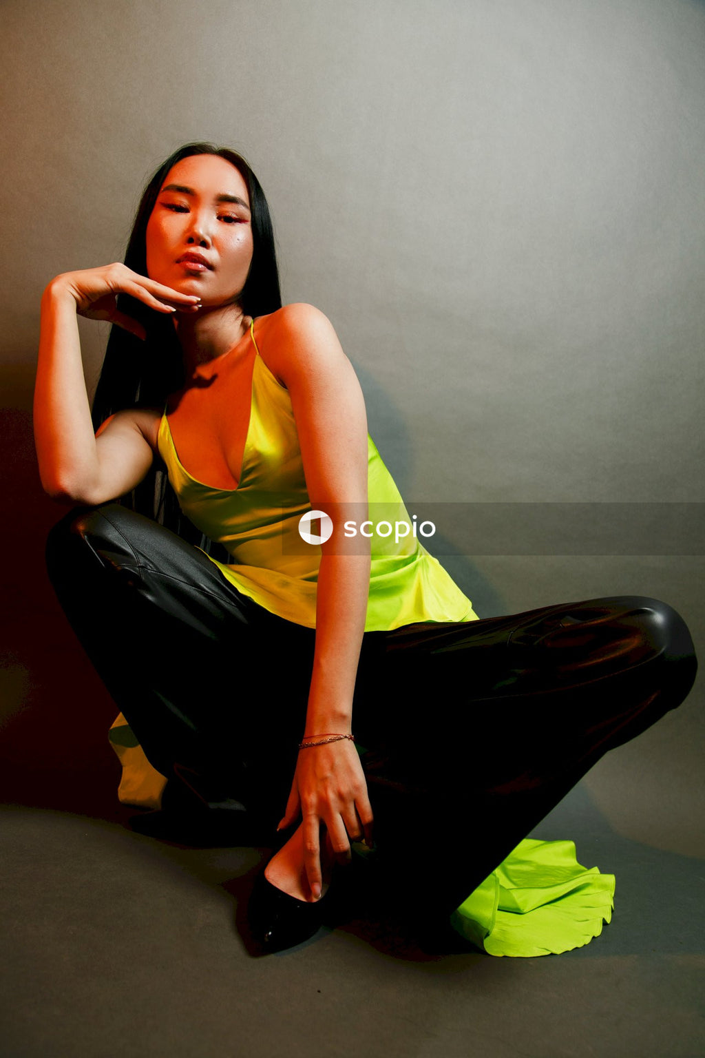 Woman in yellow sleeveless top and black skirt sitting on black chair