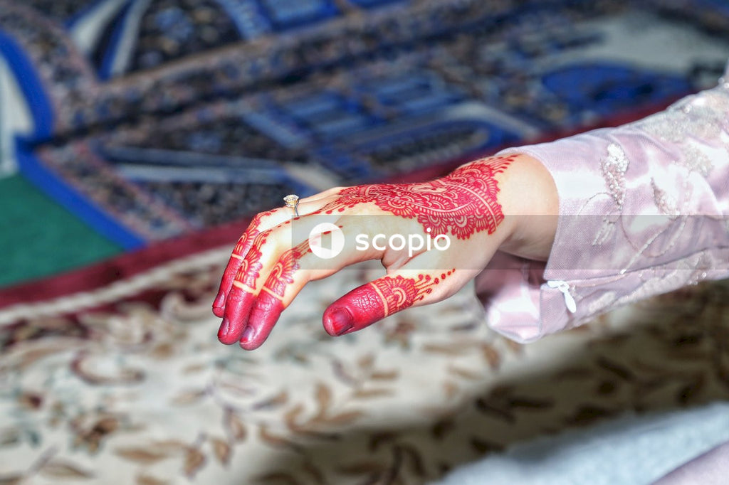 Woman's hand with red menhdi on it and engagement ring