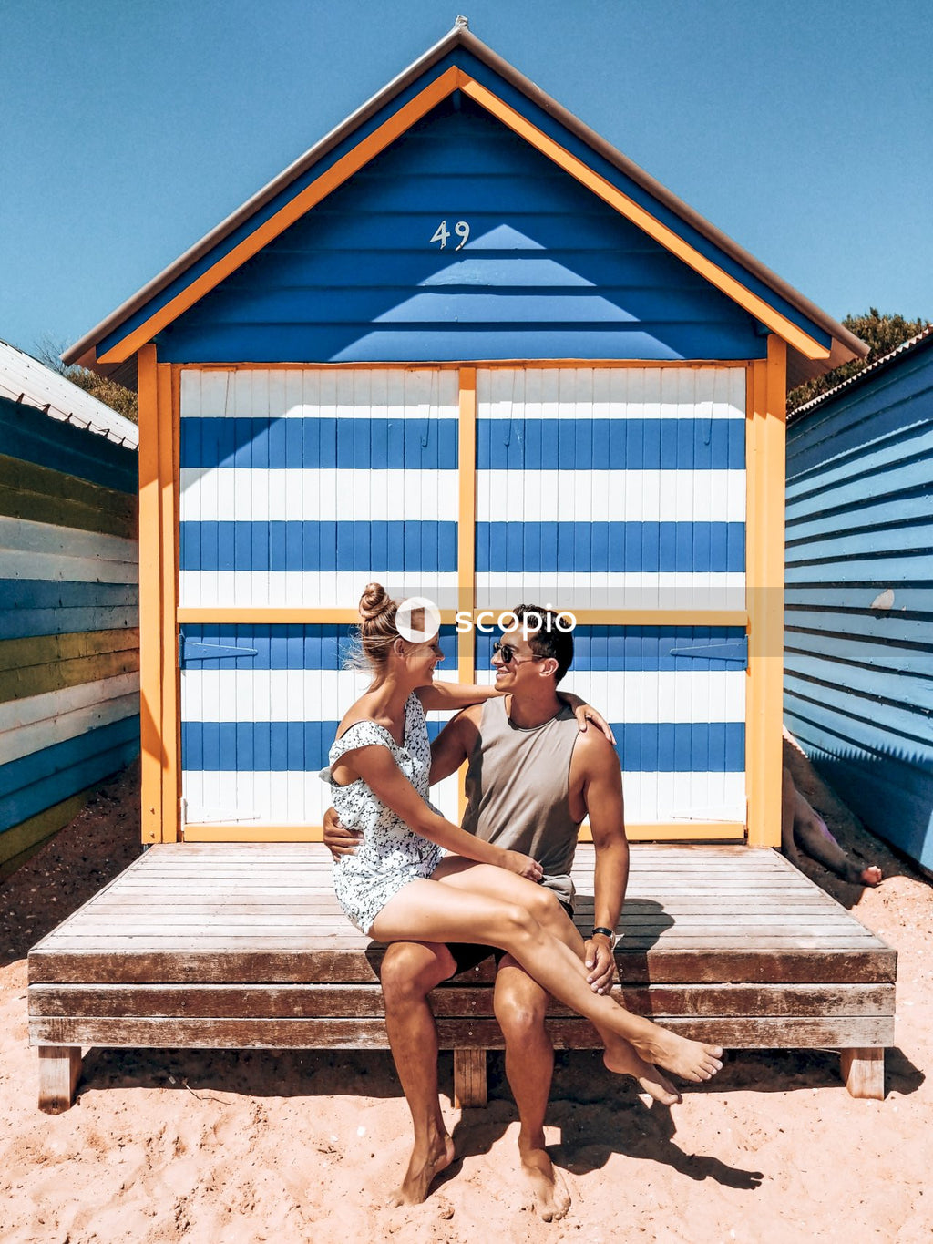 Woman sitting on lap of smiling man near beside beach house