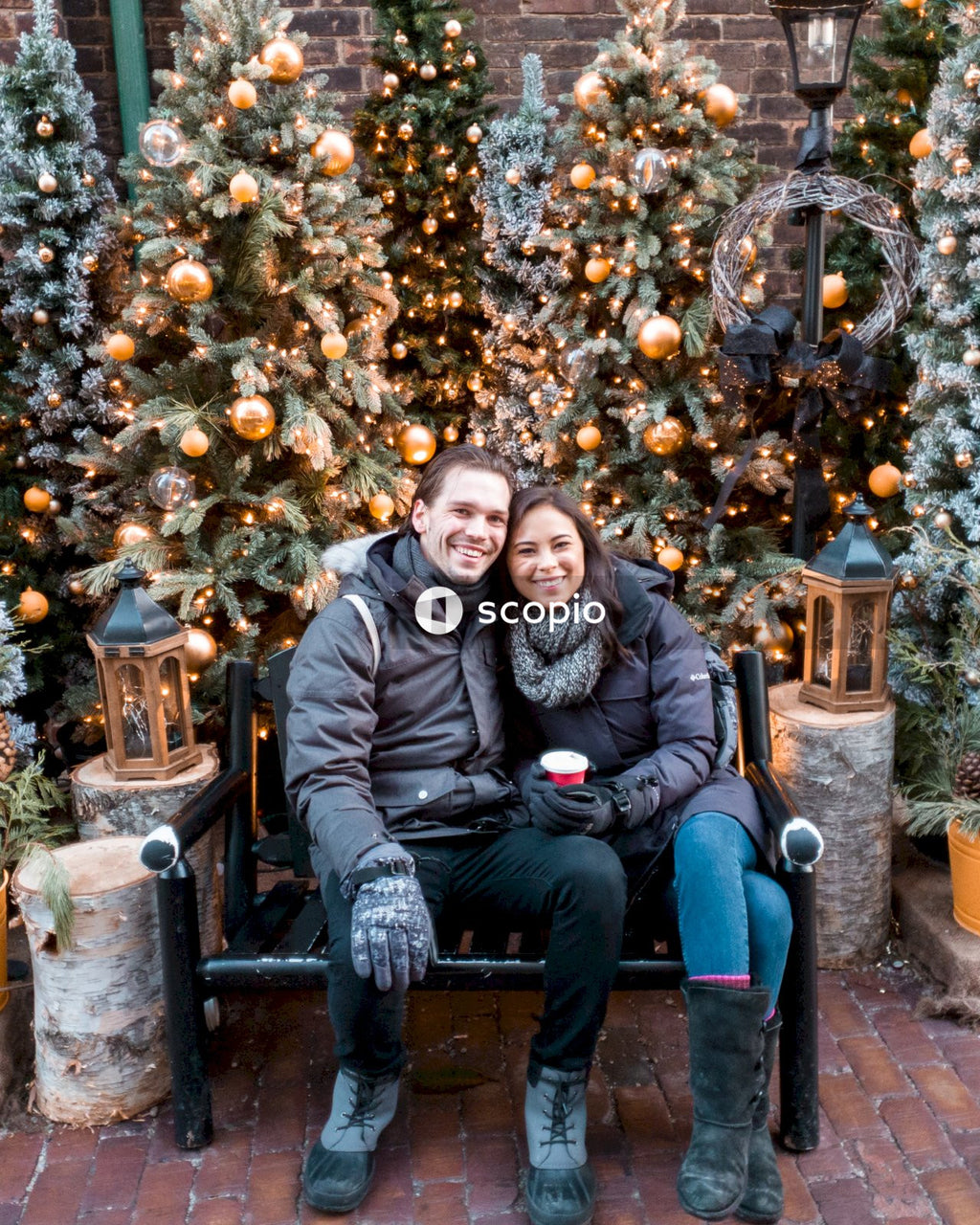 Young couple sitting on a bench against Christmas tree