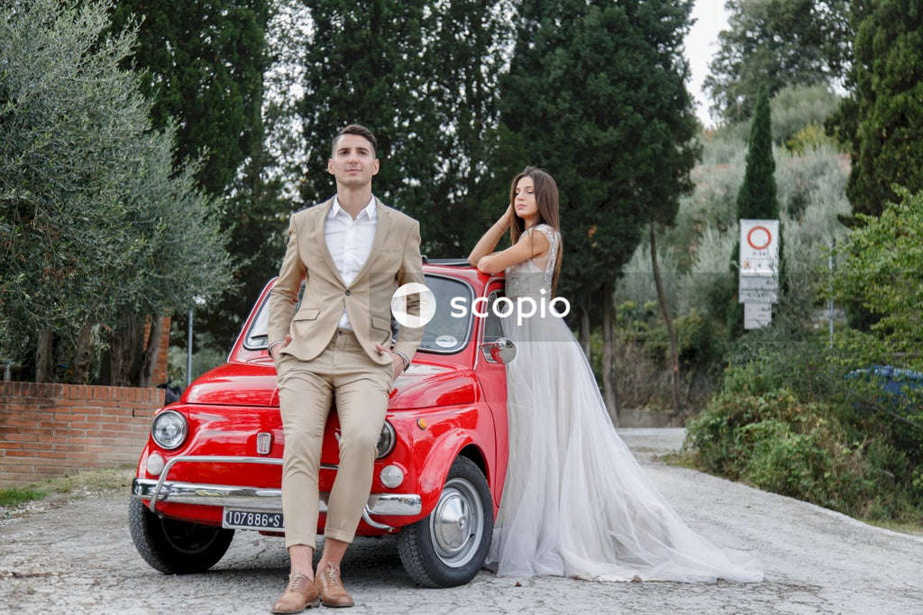 Young married couple doing a photoshoot near small red car