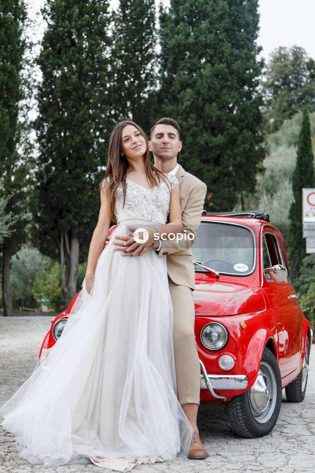 Young married couple doing a photoshoot near small red car