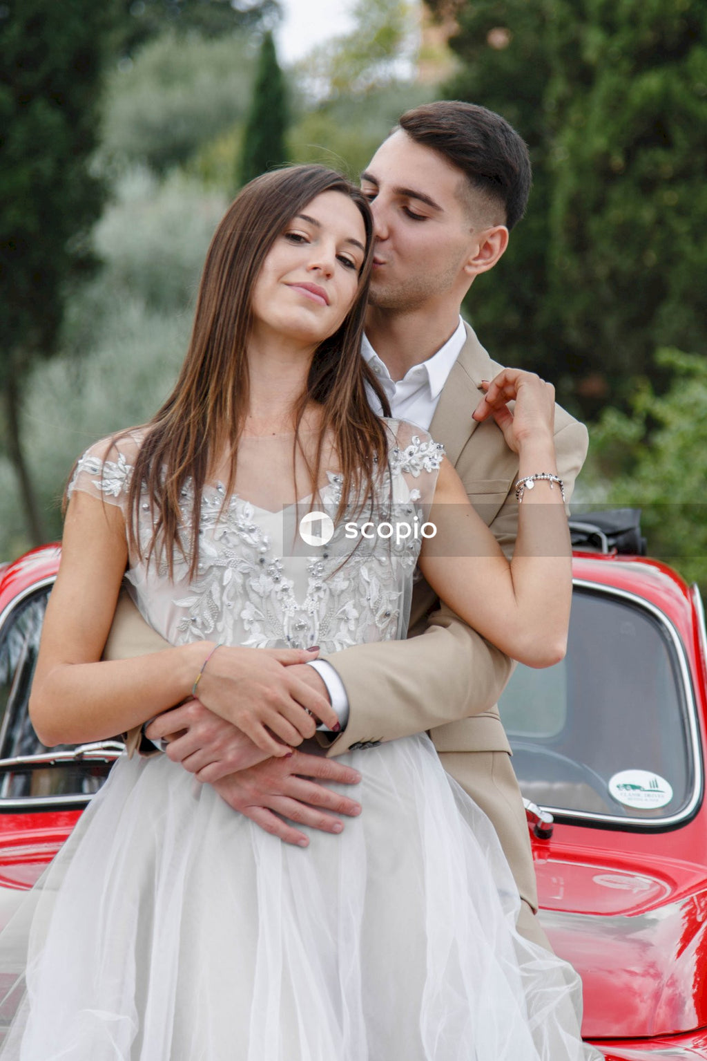 Young married couple doing a photoshoot near small red car